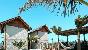Una piscina con cubierta blanca, rodeada de palmeras y una pérgola de madera.