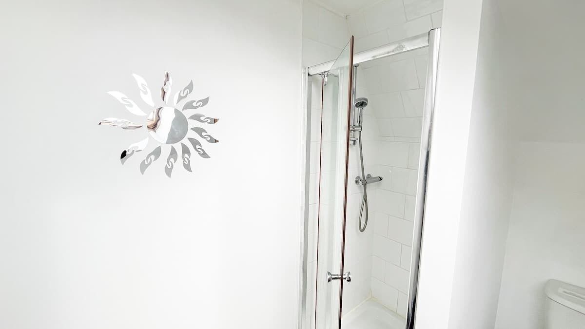 Una ducha con puerta de vidrio, un perchero y una toalla colgada en la pared.