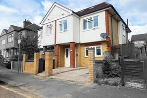 A two-story residential house with a front entrance, a satellite dish, and a gated driveway. - Spacious 4-Bed House I Free Parking & Fast Wi-Fi (Dagenham)