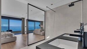 Un baño moderno con un espejo grande, una bañera y vistas al mar.