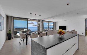 A modern living room with a large island, dining area, and a view of the sea. - Luxurious home in Makarska with sauna (Makarska)