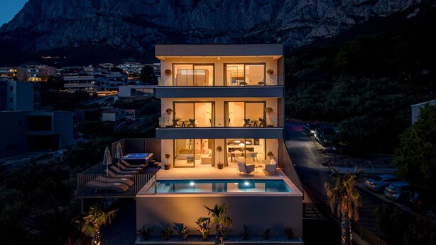Un moderno edificio de varios pisos con piscina, rodeado de un paisaje montañoso.