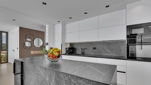 Una cocina moderna con una isla de mármol, electrodomésticos integrados y un amplio ventanal.