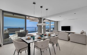 Un salon moderne comprenant un coin repas, un téléviseur et une vue sur la mer.