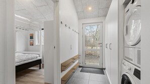 Une petite buanderie moderne, équipée d’un lave-linge, d’un sèche-linge et d’un banc.