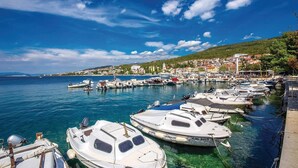 Een jachthaven met verschillende boten afgemeerd, een heldere blauwe lucht en een stad op de achtergrond.