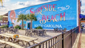Ein Wandbild von 'Surrside Beach' mit Außenplätzen und einer Holzterrasse.