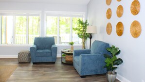 Una sala de estar con dos sillones azules, una mesita con una lámpara y una planta.