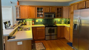A modern kitchen with wooden cabinets, stainless steel appliances, and a built-in microwave.