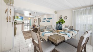 A dining area with a wooden table set for four, surrounded by upholstered chairs.