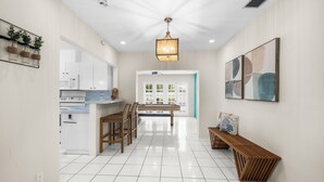A modern kitchen with white cabinets, a wooden dining table, and a bench.