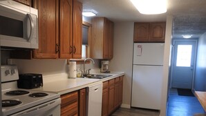 A kitchen with wooden cabinets, a microwave, stove, dishwasher, and a refrigerator.