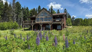 A rustic cabin with a stone facade, wooden deck, and a large window. - Lodges #72 - Rangeley Lake Overlook - ATV, Snowmobile, and close to Saddleback! (Rangeley)