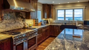 A modern kitchen with a large island, wooden cabinets, and a view of the outdoors. - Lodges #72 - Rangeley Lake Overlook - ATV, Snowmobile, and close to Saddleback! (Rangeley)