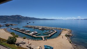 Un puerto deportivo con barcos amarrados, una playa de arena y montañas al fondo.