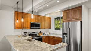 Una cocina moderna con armarios de madera, electrodomésticos de acero inoxidable y una encimera de mármol.