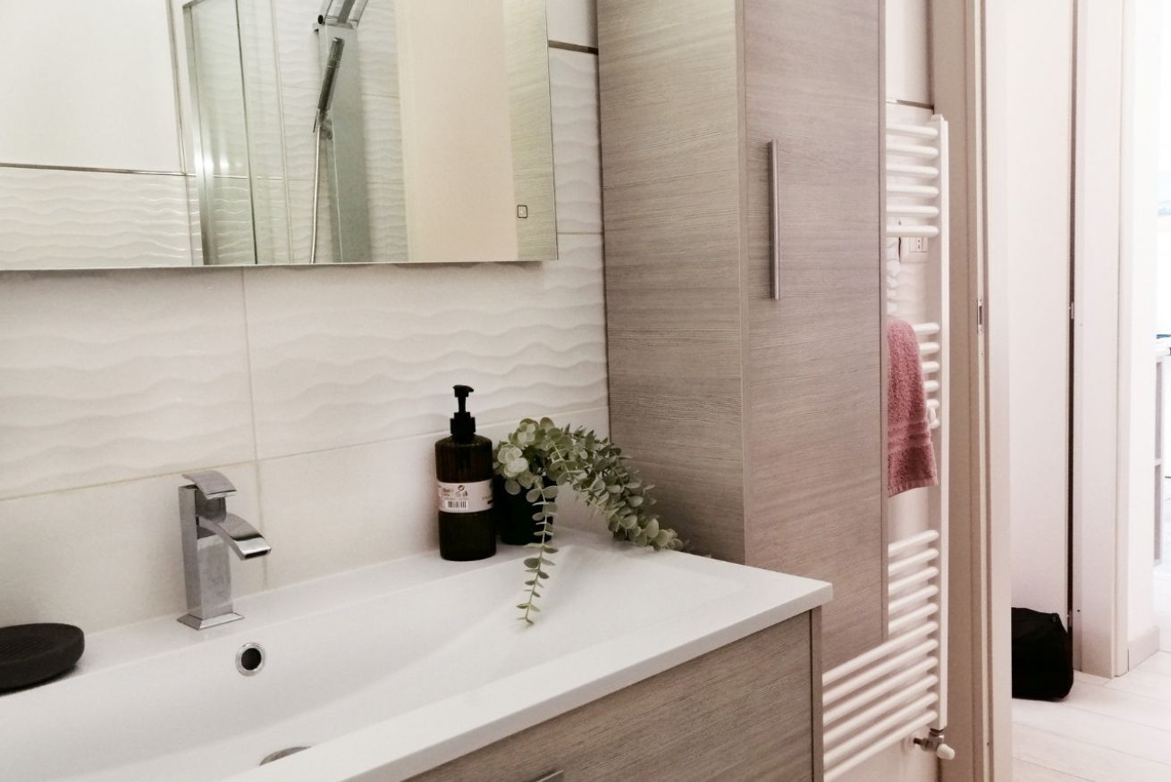 Ein modernes Badezimmer mit Waschbecken, Spiegel, Dusche und Handtuchheizkörper.