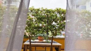 A balcony with a table and chairs, a potted plant, and a view of buildings. - Holihome_Open House FRN (Alba Adriatica)