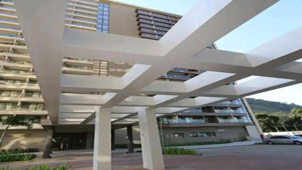 A modern building with a covered entrance area and a parking lot. - Rio Centro Stay (Rio de Janeiro)