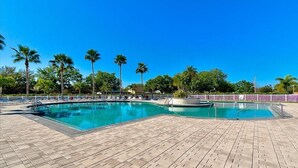 A swimming pool with a tiled deck, surrounded by palm trees and a clear blue sky. - Paradise 4 Bedroom Heated Pool Home Near IMG Academy and Siesta Key Beach (Bradenton)