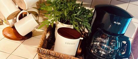 Een keukentrap met een koffiehoek, inclusief een koffiezetapparaat, een koffiemok en een plant.