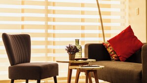 A room with a sofa, a chair, a small table, and a window with blinds. - Charming 1-bedroom apartment in wonderful Barranquilla with AC, WiFi (Barranquilla)