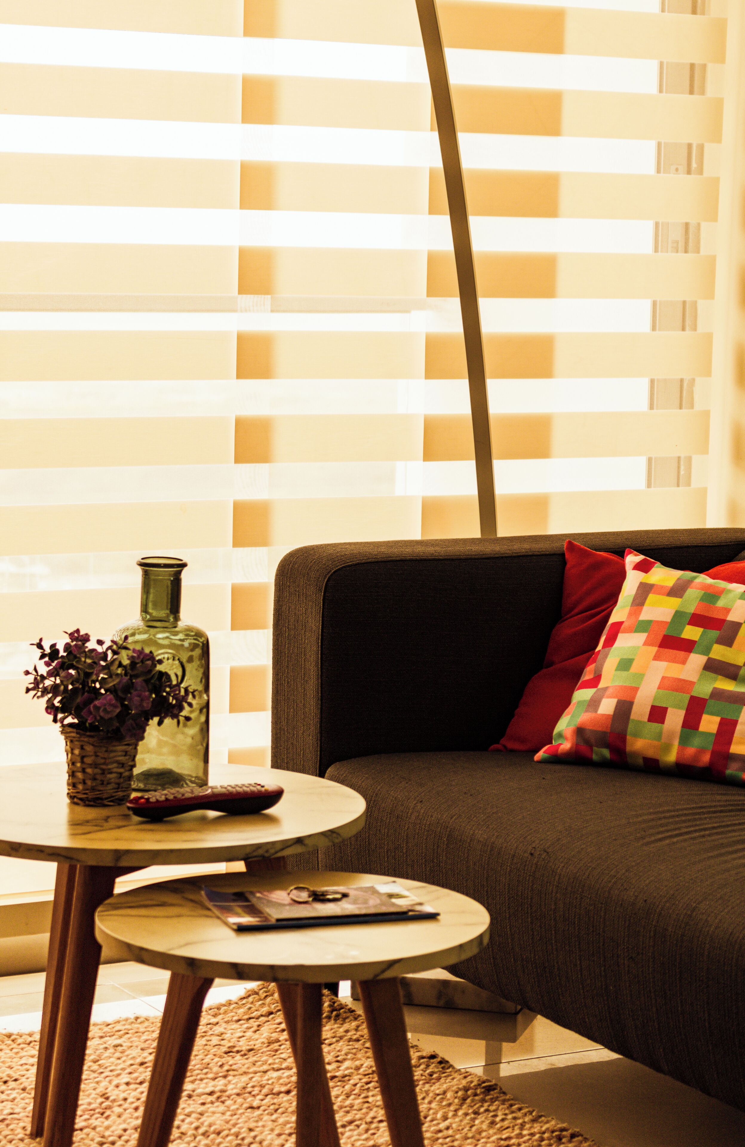 A living room with a sofa, a small round table, and a vase with flowers.