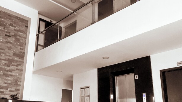 A modern lobby with a glass railing, a reception desk, and an elevator. - Charming 1-bedroom apartment in wonderful Barranquilla with AC, WiFi (Barranquilla)