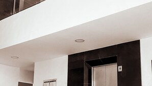 A modern elevator with a metallic finish, a glass panel on the left, and a control panel on the right. - Charming 1-bedroom apartment in wonderful Barranquilla with AC, WiFi (Barranquilla)