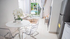 Una cocina moderna con una mesa y sillas blancas, un refrigerador y vistas a una piscina exterior.
