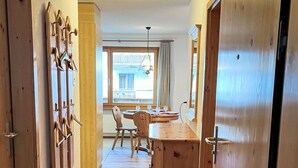 Un couloir avec un plancher en bois, un coin repas avec une table et des chaises, et une grande armoire en bois.