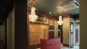 Ein Korridor mit einem roten Schreibtisch, einer Kronleuchter-Beleuchtung und einer goldenen Wandverkleidung.