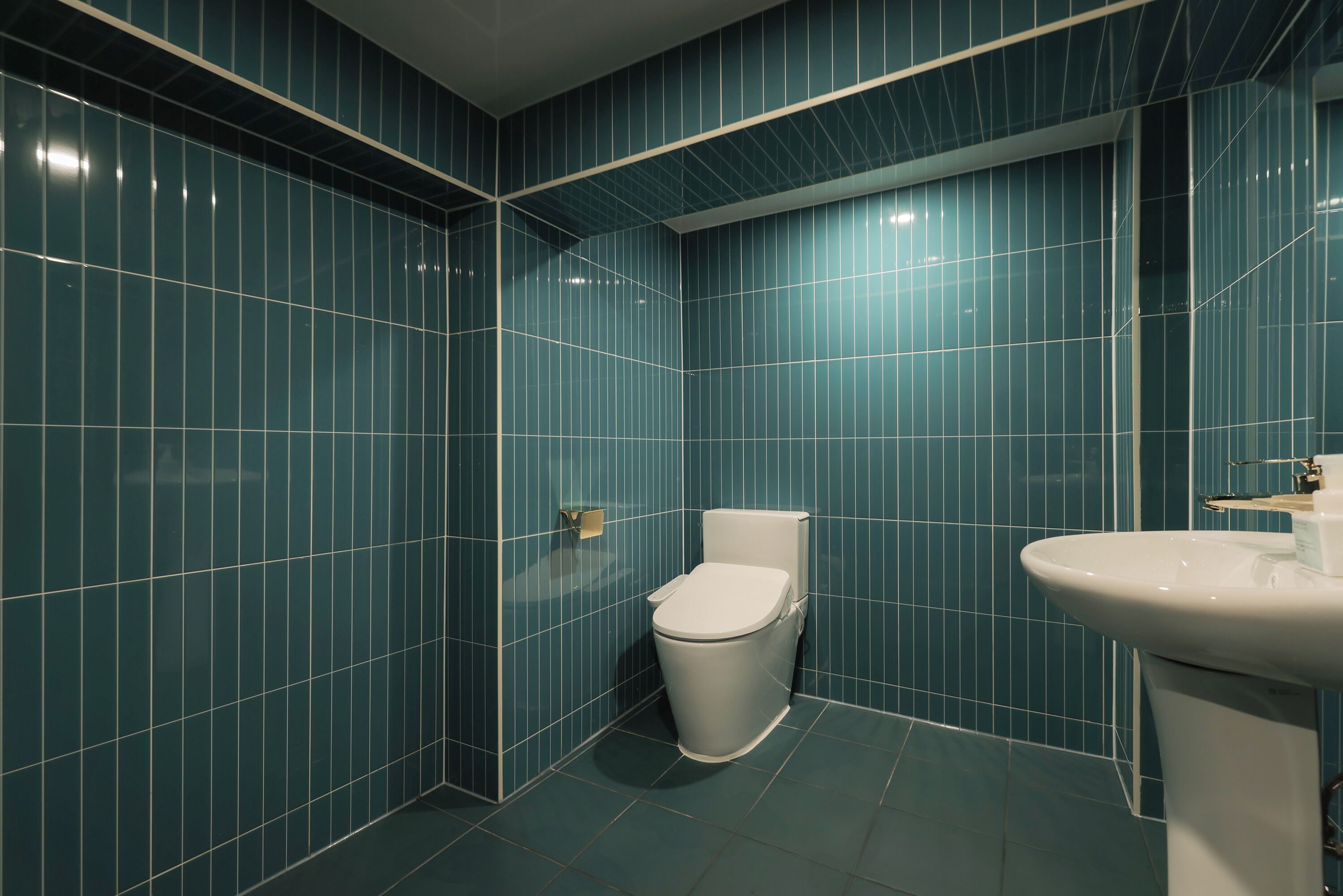 Un bagno con pareti piastrellate di blu, un water bianco e un lavandino bianco.