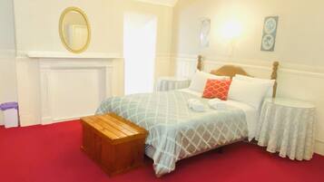 A bedroom with a bed, a wooden bench, a mirror, and a fireplace.