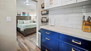 Una cocina moderna con armarios blancos, una encimera azul y un portalápices de madera.