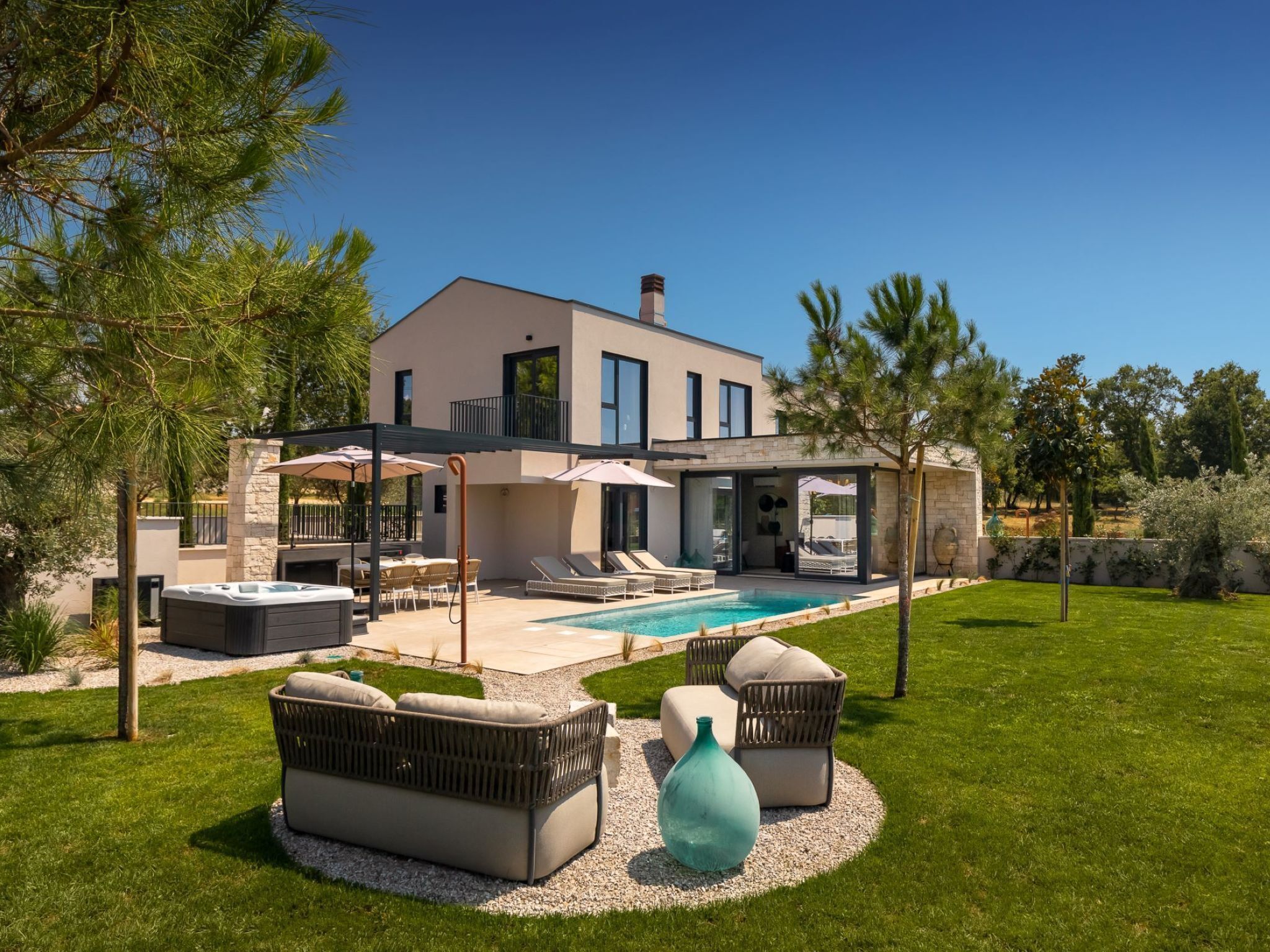 A modern two-story house with a swimming pool, outdoor seating, and a well-maintained garden.