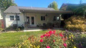 A house with a covered porch, a lawn with colorful flowers, and a garden area.