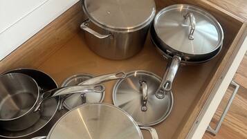 A kitchen drawer with various stainless steel pots and pans.