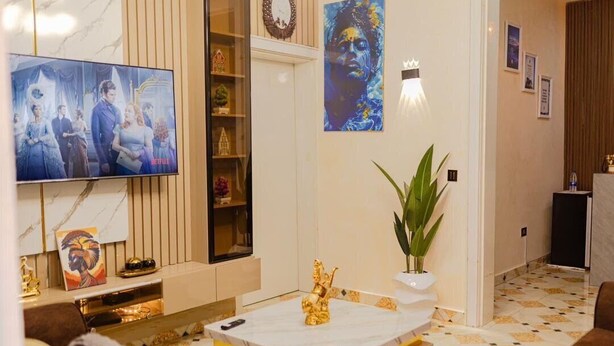 Una sala de estar moderna con un televisor de pantalla plana, una mesa de centro de mármol y una estatua dorada decorativa.