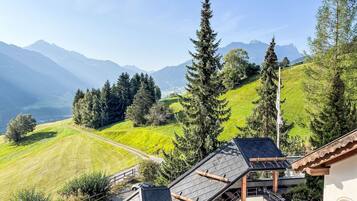Une vue sur une montagne, avec un sentier menant à un bâtiment doté d’un toit en pente et de poutres en bois.