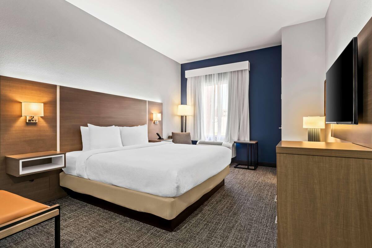 Una habitación de hotel con una cama grande, mesitas de noche, un escritorio y un televisor.