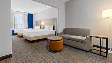 Ein Hotelzimmer mit einem Bett, einer Couch, einem kleinen runden Tisch und einer Lampe.