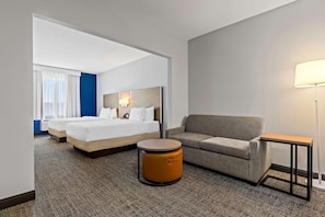 A hotel room with a bed, a sofa, a small round table, and a lamp. - Spark by Hilton Catoosa Tulsa (Catoosa)