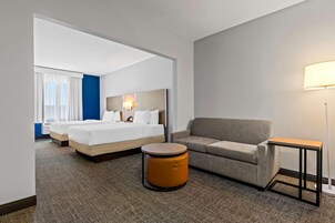 Una habitación de hotel con una cama, un sofá, una mesita redonda y una lámpara.