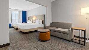 Una camera d'albergo con un letto, un divano, un tavolino rotondo e una lampada.