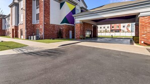 Un edificio a più piani con un evidente cartello 'Spark', un'area di parcheggio coperta e un prato curato.
