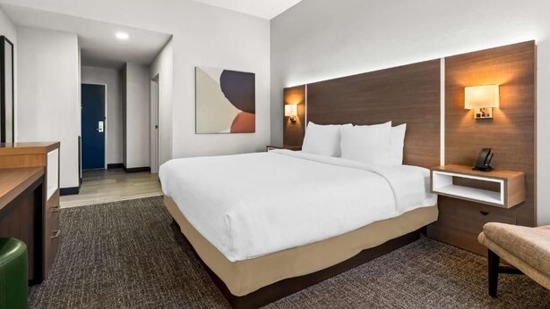 Una habitación de hotel con una cama grande, mesitas de noche, un escritorio y una silla.