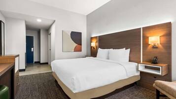 A hotel room with a large bed, bedside tables, a desk, and a chair.