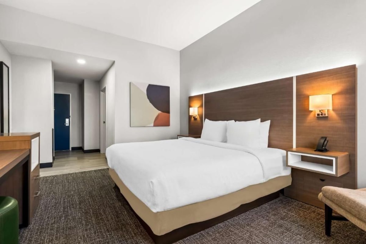 Une chambre d’hôtel avec un grand lit, des tables de chevet, un bureau et une chaise.