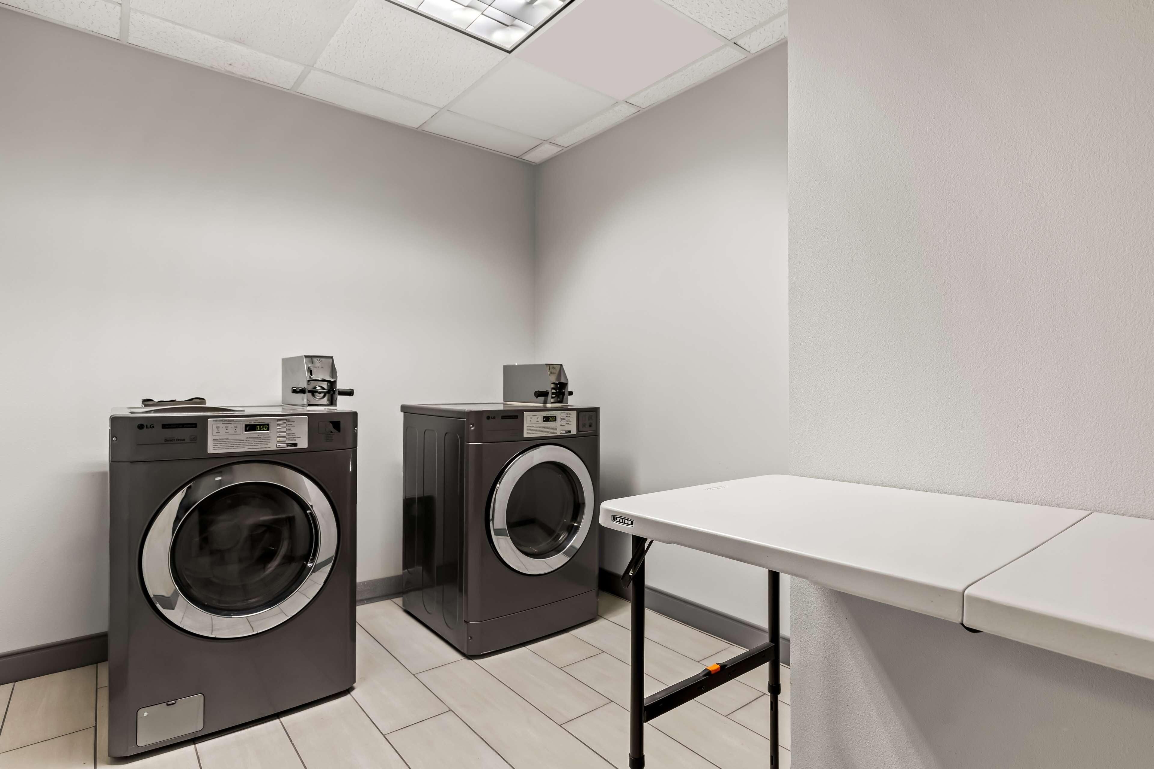A laundry room with two front-loading washing machines and a table.